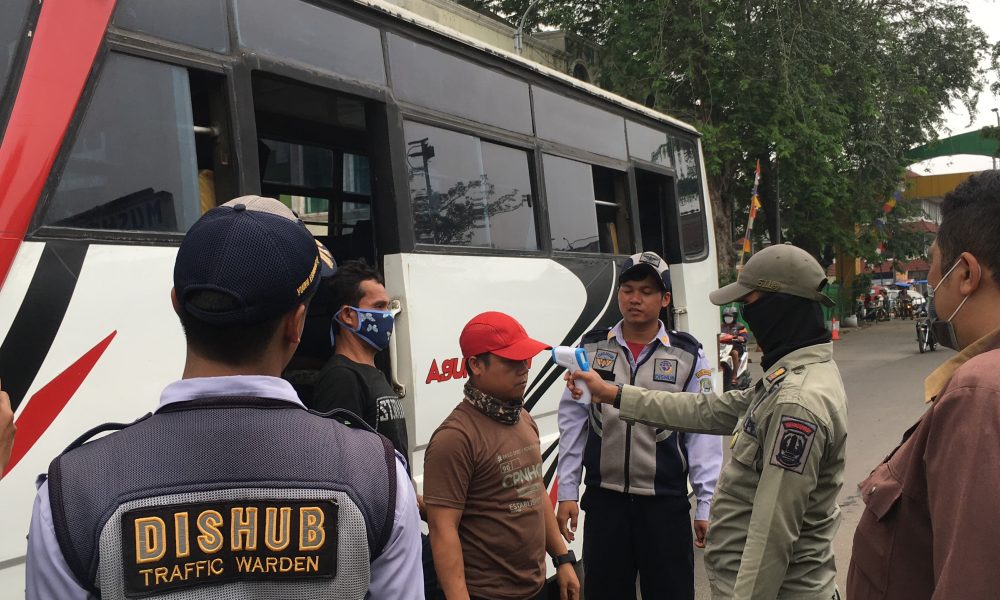 Pemeriksaan suhu tubuh di depan gerbang terminal induk bekasi bagi pendatang pengguna transportasi umum
