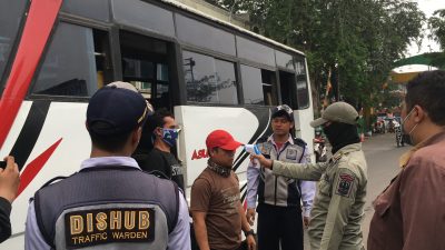 Pemeriksaan suhu tubuh di depan gerbang terminal induk bekasi bagi pendatang pengguna transportasi umum