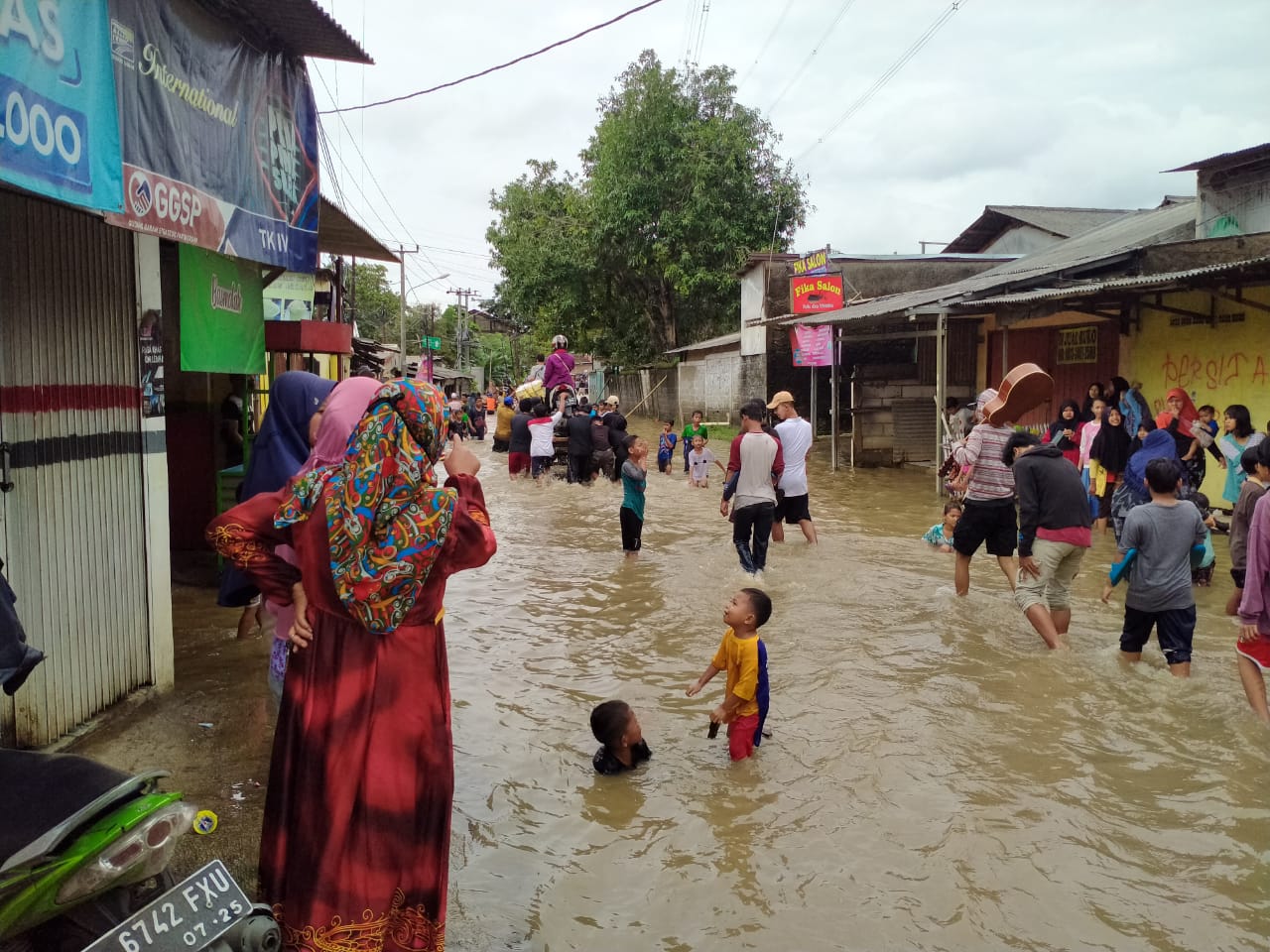 Warga di Jalan Karang Satria, Kampung Babakan, Kabupaten Bekasi, saat mengawasi anak-aaknya bermain banjir, Jumat (19/2/2021). Foto: Gobekasi.id