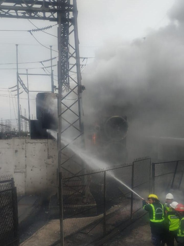 Petugas Damkar memdamkan api yang membakar gardu listrik di Jalan Inspeksi Kalimalang