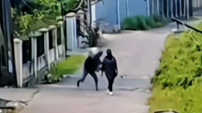 Tangkapan layar seorang ODGJ menimpuk kepala guru wanita menggunakan batu.