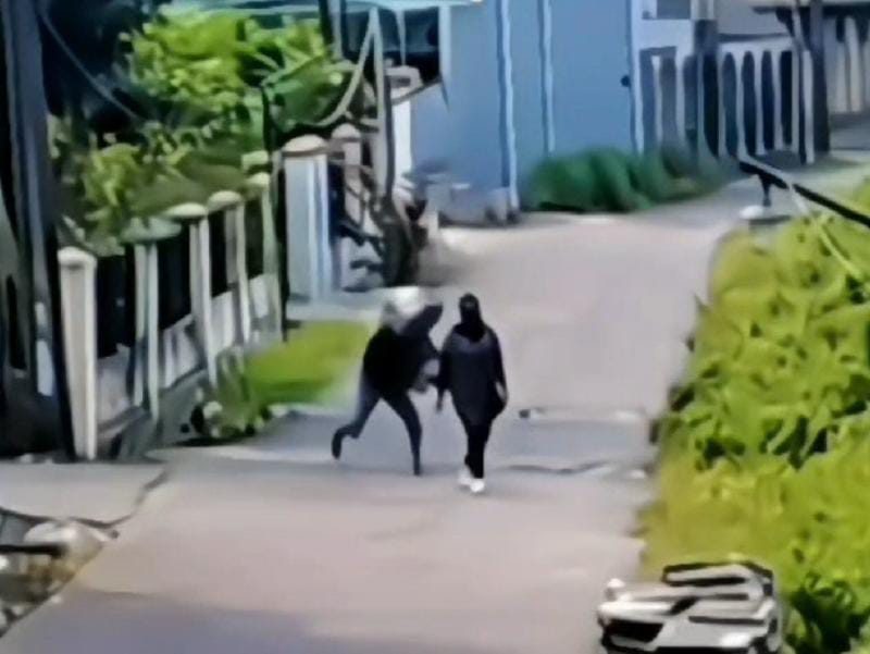 Tangkapan layar seorang ODGJ menimpuk kepala guru wanita menggunakan batu.