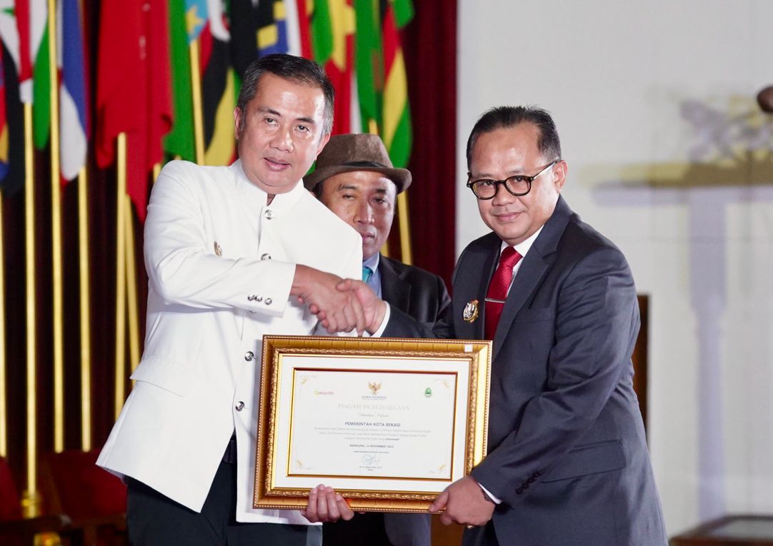 Pj. Gubernur Jawa Barat, Bey Machmudin memberikan pelakat penghargaan kepada Pj Wali Kota Bekasi Raden Gani Muhamad. Foto: Ist