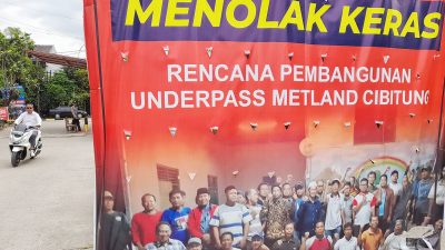 Warga melintasi spanduk penolakan rencana pembangunan underpass Metland Cibitung di Perumahan Telaga Harapan Desa Telagamurni Kecamatan Cikarang Barat Kabupaten Bekasi, Senin (17/2). ARIESANT/RADAR BEKASI