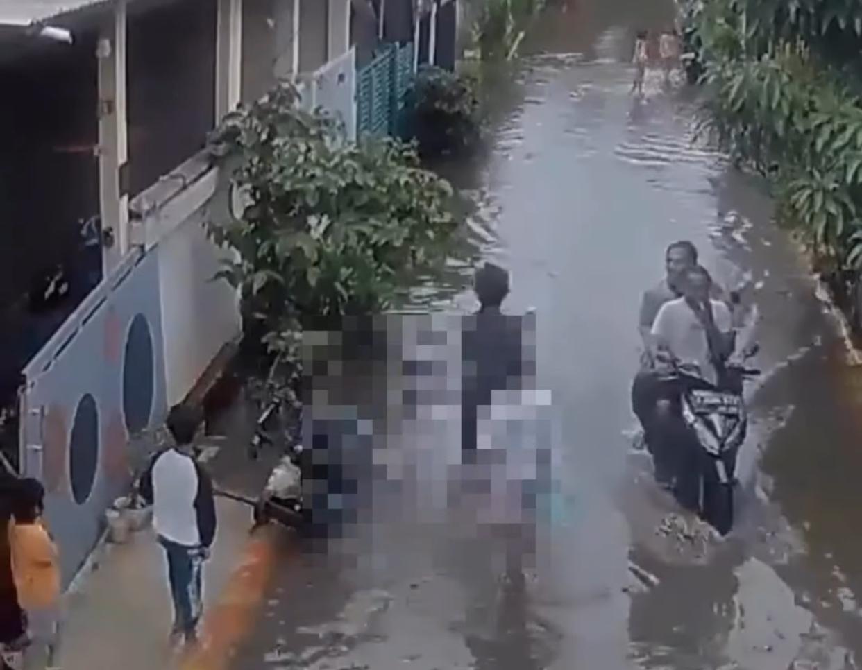 Tangkapan layar seorang pria melempar anaknya yang masih balita ke genangan banjir di Bekasi.