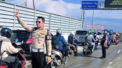 Pejabat Penanggung Jawab Ruas (PJR) Cikampek, AKP Sandy Titah Nugraha saat memberikan aba - aba pemotor yang bekerja untuk melalui Tol Cibitung - Tanjung Priok melalui GT Gabus, Rabu (5/3/2025).