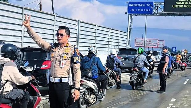 Pejabat Penanggung Jawab Ruas (PJR) Cikampek, AKP Sandy Titah Nugraha saat memberikan aba - aba pemotor yang bekerja untuk melalui Tol Cibitung - Tanjung Priok melalui GT Gabus, Rabu (5/3/2025).
