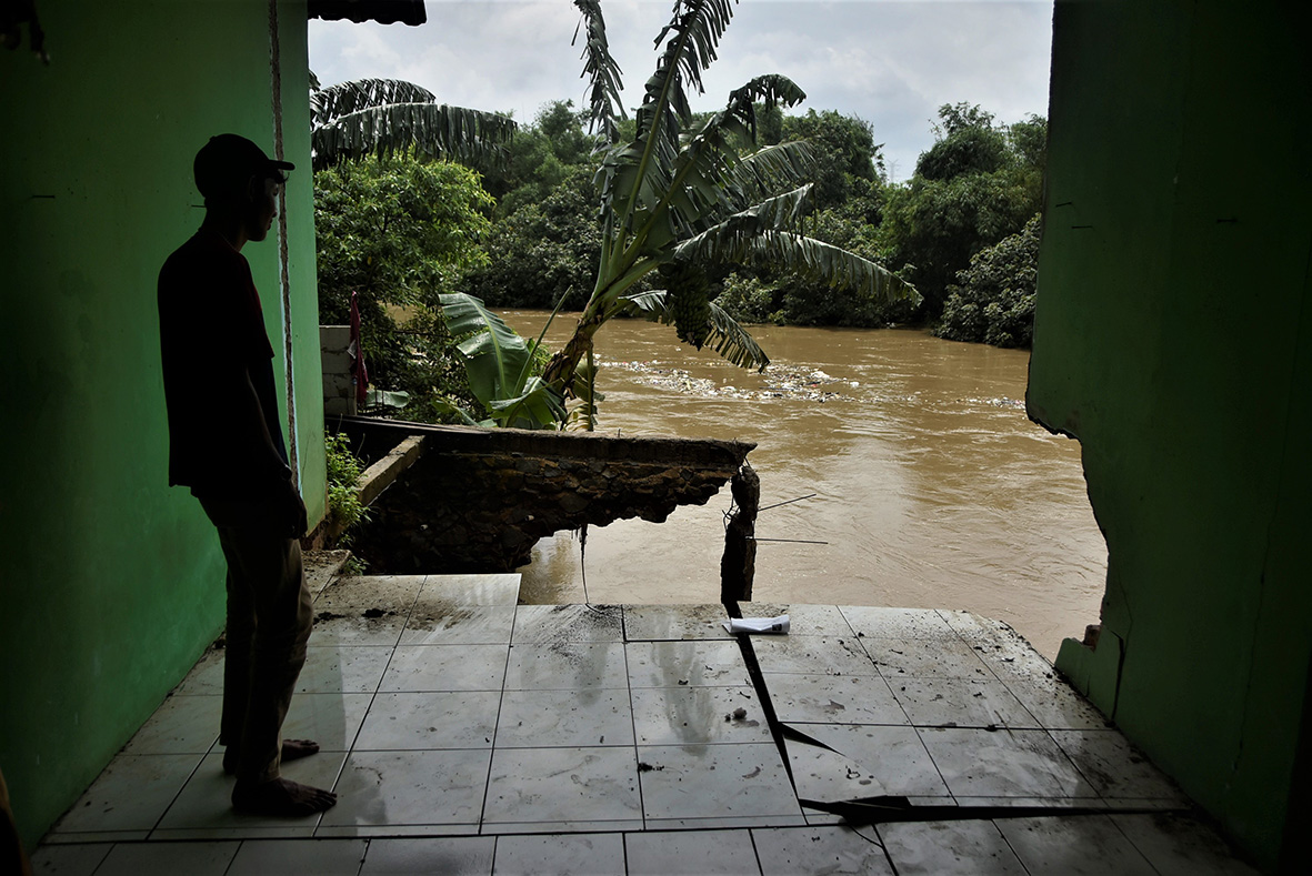 Warga mengamati rumahnya yang longsor akibat tergerus aliran Kali Bekasi di RT03/RW02 Teluk Pucung Bekasi Utara, beberapa waktu lalu. RAIZA SEPTIANTO/RADAR BEKASI.
