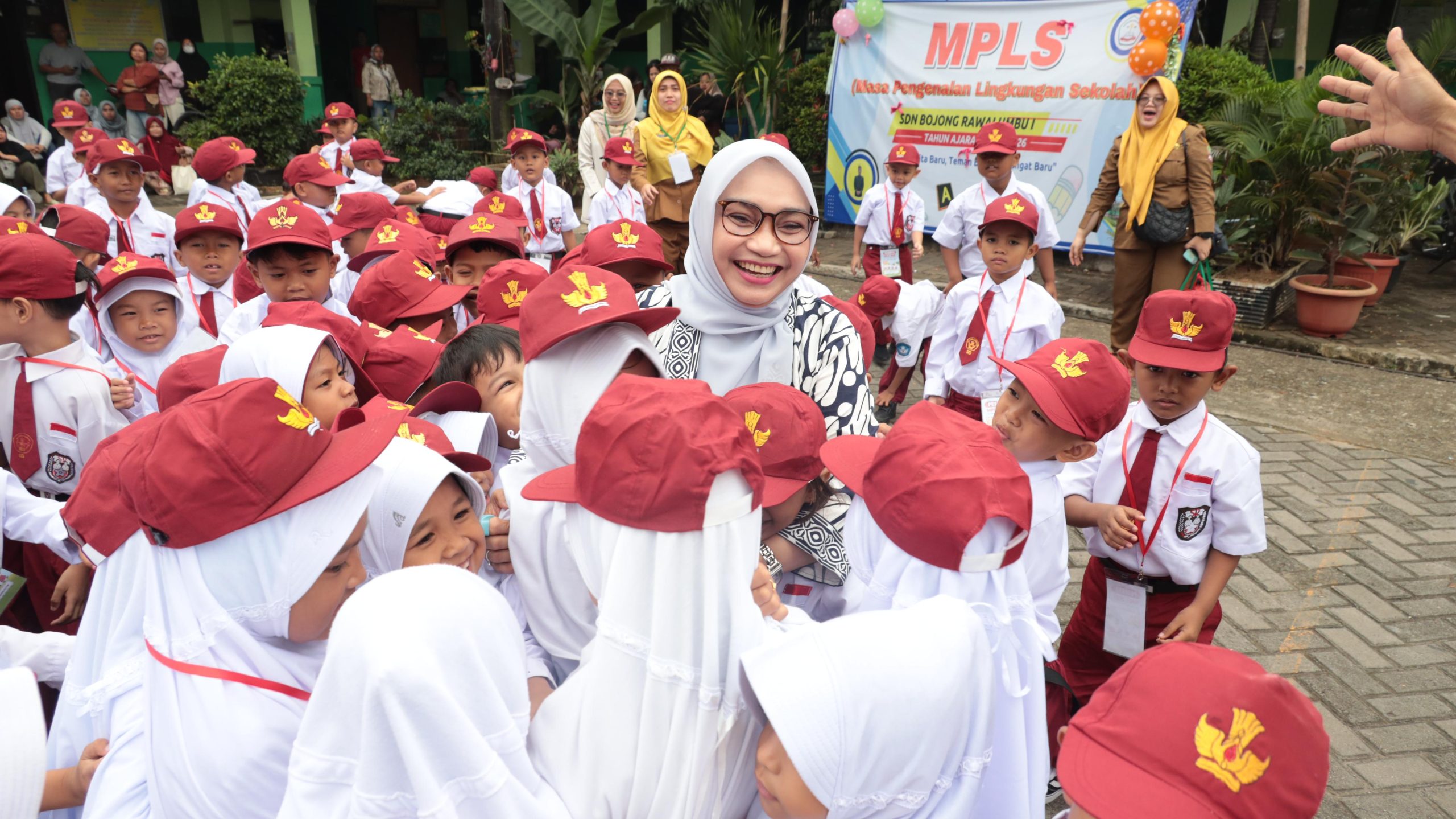 Kota Bekasi - Ketua Tim Penggerak PKK Kota Bekasi, Wiwiek Hargono Tri Adhianto, melakukan kunjungan langsung ke beberapa sekolah yang melaksanakan kegiatan Masa Pengenalan Lingkungan Sekolah (MPLS) di hari pertama tahun ajaran baru 2025/2026, Senin (14/7/2025).