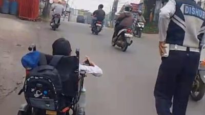 Kota Bekasi - Anggota Dinas Perhubungan (Dishub) Kota Bekasi bernama Ikhwan Ansari, yang mengawal langsung seorang siswa disabilitas menuju sekolah di kawasan Zamrud, Mustikajaya, pada Senin pagi (14/7/2025).