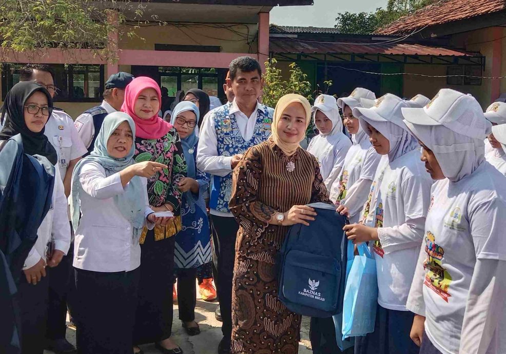 Kabupaten Bekasi - Wakil Bunda Forum Anak Daerah Kabupaten Bekasi, Nia Asep Surya Atmaja didampingi Kepala Disdukcapil, Carwinda, memberikan bantuan peralatan sekolah dari Baznas dan Bank Bjb, kepada puluhan siswa, di acara Botram Sekolah dan peringatan Hari Anak Nasional ke-41, di SMPN 1 Tambelang, Rabu (23/7/2025).