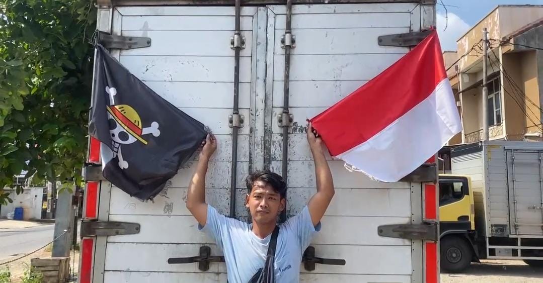 Kota Bekasi - Rahmat (30), sopir truk asal Banyumas, Jawa Tengah, mengaku sengaja memasang bendera Jolly Roger—simbol bajak laut dalam serial anime One Piece—sebagai bentuk aspirasi sosial saat melintas di Kota Bekasi, Rabu (6/8/2025). Foto: Septian/Gobekasi.id