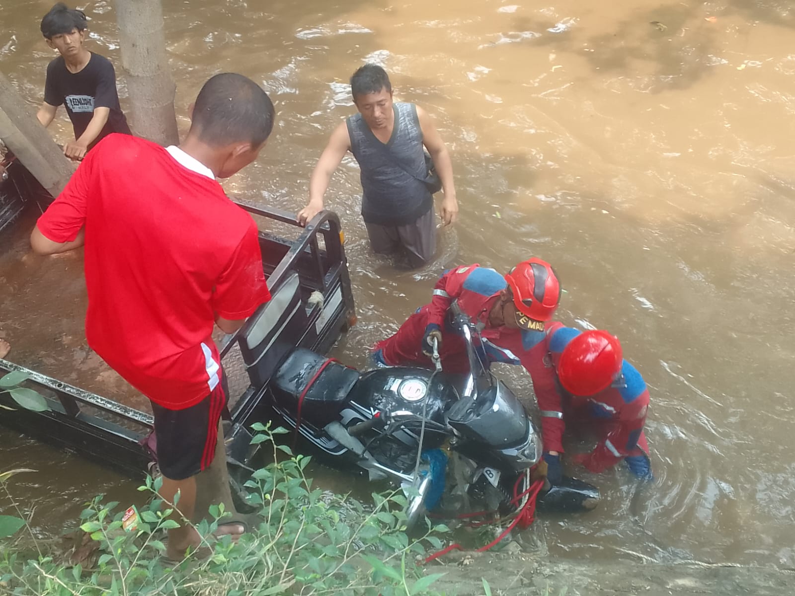Kota Bekasi - Baktor bermuatan tabung gas dan air mineral tercebur ke kali di Jalan Jamrud Bunderan Kodok, Kelurahan Padurenan, Kecamatan Mustika Jaya, Kota Bekasi, Rabu (13/8/2025).  Foto: Ist