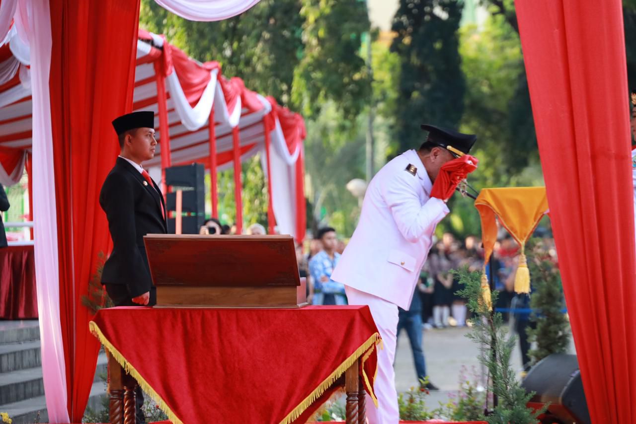 Kota Bekasi - Wakil Wali Kota Bekasi, Abdul Harris Bobihoe, mencium bendera merah putih saat bertindak sebagai inspektur upacara dalam parade senja penurunan bendera merah putih di Alun-alun Hasibuan, Kota Bekasi, Minggu (17/8/2025). Foto: Ist/Gobekasi.id
