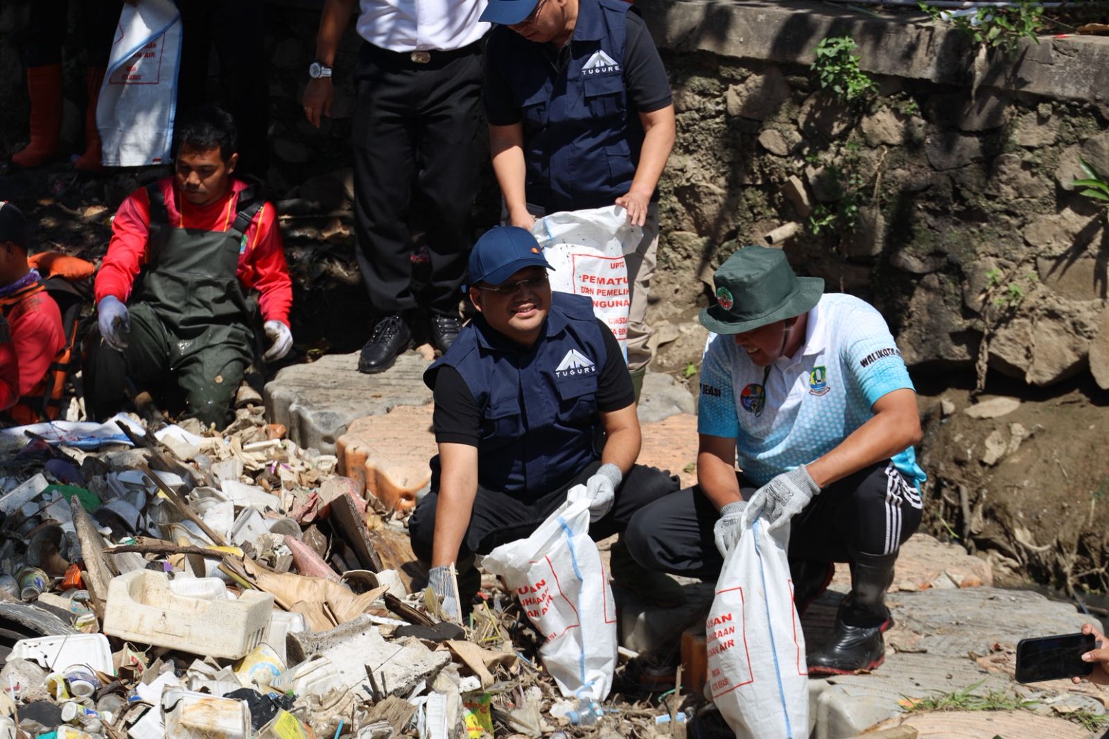 Kota Bekasi - Wali Kota Bekasi, Tri Adhianto, turun langsung bersama Pandawara Group dan PT Tugu Reasuransi Indonesia. memberishkan sampah di Kali Kapuk. Foto: Ist/Gobekasi.id
