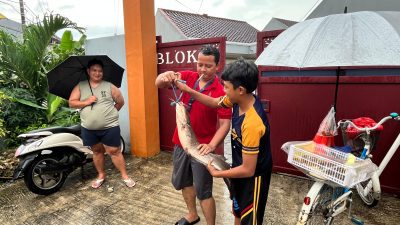 Kota Bekasi - Warga menangkap ikan lele yang meluber akibat luapan folder air di kawasan Danau Wisma Jaya, Bekasi Timur, sejak Minggu malam (18/1/2026). Foto: Septian/Gobekasi.id.