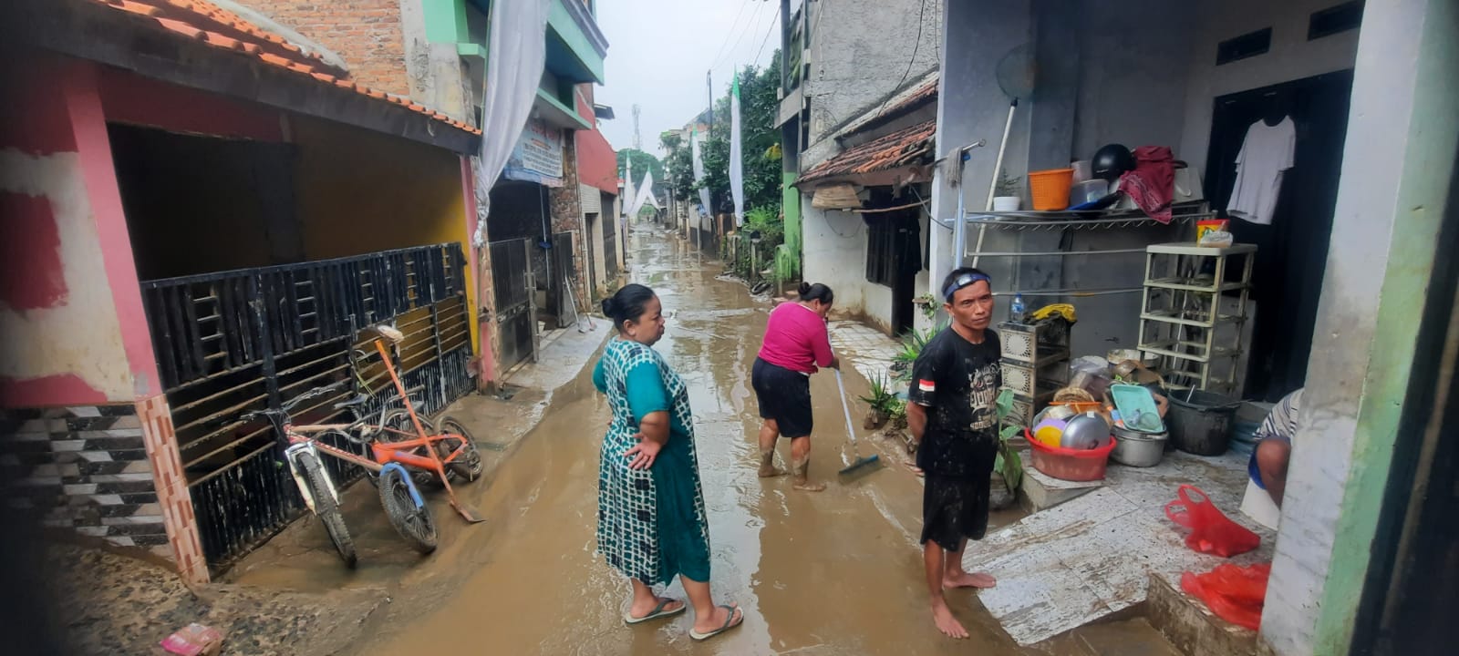 Kota Bekasi - Warga Gang Mawar, Margahayu, Bekasi Timur, membersihkan sisa lumpur tebal pasca banjir akibat meluapnya Kali Bekasi, Kamis (12/2/2026). Foto: Septian/Gobekasi.id.