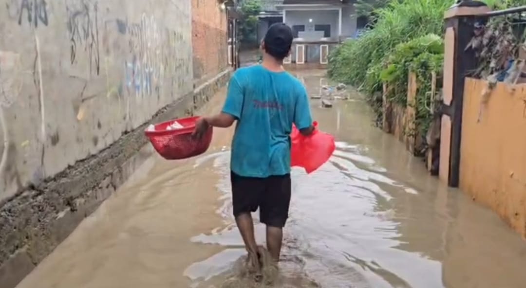 Kota Bekasi - Warga Gang Mawar, Kelurahan Margahayu, Kecamatan Bekasi Timur, melintasi lumpur--bekas banjir yang menerjang pada Kamis (12/2/2026) dini hari akibat meluapnya Kali Bekasi, Rabu (11/2/2026) malam. Foto: Gobekasi.id.