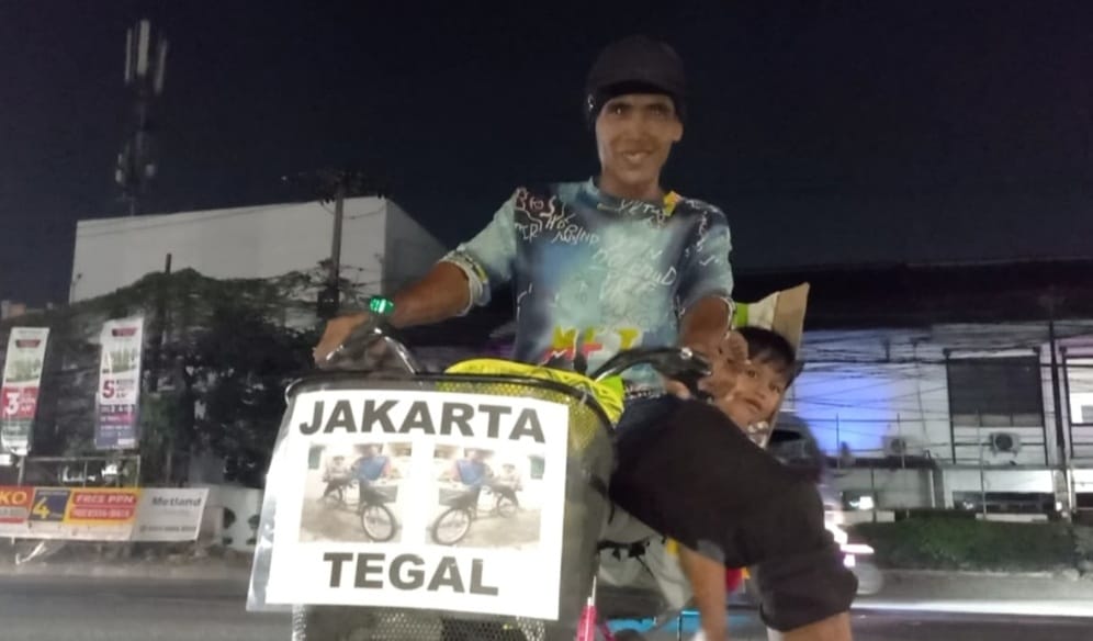 Kabupaten Bekasi - Waskum, pria yang memilih mudik dengan mengayuh sepeda dari Jakarta menuju Tegal, Jawa Tengah, sambil membawa anaknya saat melintas di Kawasan Tambun, Kabupaten Bekasi. Foto: Septian/Gobekasi.id.