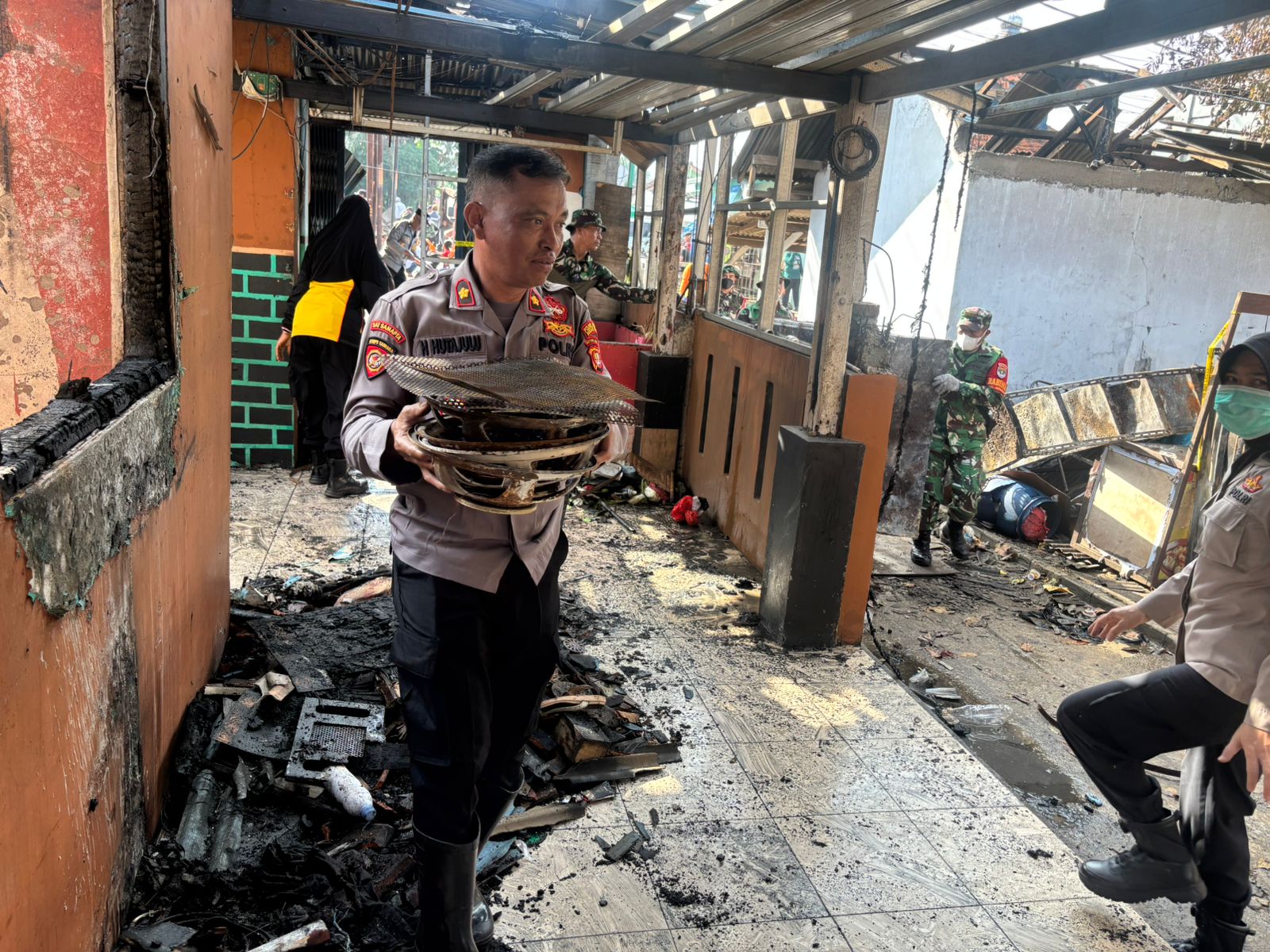 Kota Bekasi - Petugas Polres Metro Bekasi Kota saat membangtu pembersihan bangunan rumah warga pasca ledakan SPBE Cimuning