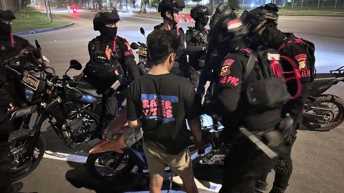 Bekasi - Personel Brimob Polda Metro Jaya saat mengamankan pemuda yang diduga menjadi joki balap liar di kawasan MM2100. Foto: Ist