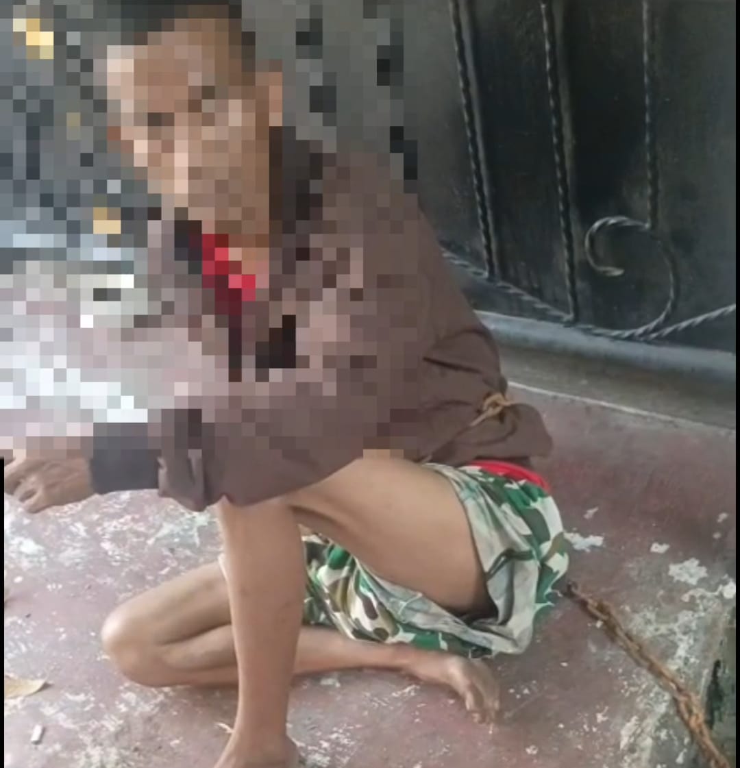 Bekasi - Seorang pria dipasang rantai besi pada tubuhnya dan diikatkan ke pagar rumah warga kawasan Jalan Makmur IV, RW 14, Kelurahan Bahagia, Kecamatan Babelan, Kabupaten Bekasi. Foto: Ist/Gobekasi.id.