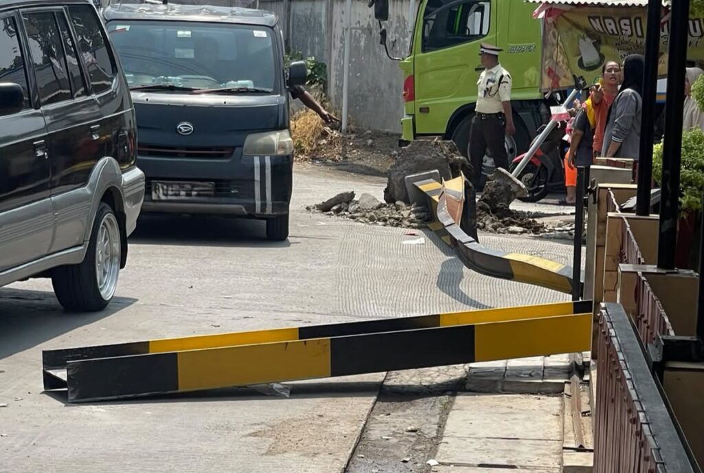 Bekasi - Truk Fuso menabrak portal di Jalan Caringin, Bekasi, Senin (21/9/2026). Tiang roboh dan menimpa pengendara Honda Vario hingga terluka. Foto: Ist/Gobekasi.id.